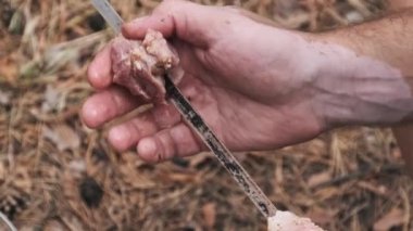 Vitiligo 'su olan bir adam bonibonlar için metal bir şişin üzerine salamura edilmiş domuz eti yerleştiriyor. Piknik ve aşçılık kavramı.