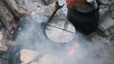 Adamın biri bir tencere çorbayı karıştırıyor. Kamp ateşinin üstünde köpürüyor. Sıcak çorbadan buhar yükseliyor. Tavuğun kalçaları tavanın içinde cızırdıyor..