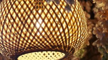 Güzel bir kakaolu abajur yapay çiçeklerin arka planına asılarak rahat ve sıcak bir atmosfer yaratıyor. Ev dekorasyonu, iç tasarım ve yaşam tarzı projeleri için mükemmel..