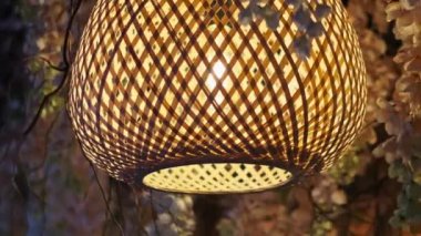 Güzel bir bambu lambası narin suni çiçeklerin arasında nazikçe sallanarak dingin ve davetkar bir ortam yaratır. Ev dekorasyonu, rahatlama ve Asya estetiği temalı