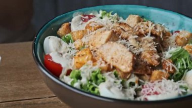 Taze hazırlanmış Sezar salatası ızgara tavuk, kızarmış ekmek, parmesan peyniri ve kremalı sos. Görsel olarak çekici bir şekilde sunulan klasik bir yemek..