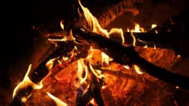 Yoğun alevler dans ediyor ve bir kamp ateşinde titreşiyor, karanlığa karşı sıcak bir parıltı saçıyor, büyüleyici bir ortam yaratıyor..