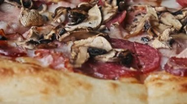 Erimiş peynirli, mantarlı, pastırmalı, salamlı lezzetli bir pizzanın aşırı yakından çekimi.