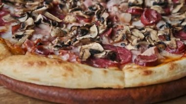Peynirli, mantarlı, pastırmalı, salamlı ve sosisli taze pişmiş pizza. Dokuma ve ağız sulandırma cazibesini gösteriyor. Yemek blogları için mükemmel..