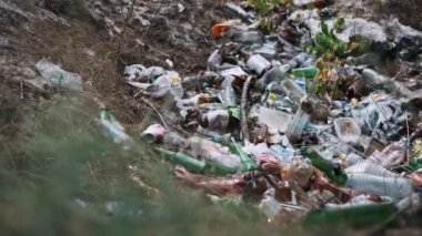 Plastik şişeler, ambalajlar ve poşetlerle dolu bir orman zemininin yakınında. Çevre kirliliği sorunu.