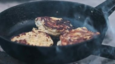 Kamp ateşinin üstünde cızırdayan tavuk butlarını kapatın. Duman yükseliyor ve ağız sulandıran bir koku yaratıyor..