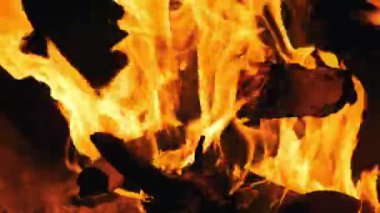 Yoğun turuncu alevler, büyüleyici bir kamp ateşinde odun yakarak karanlık geceye karşı sıcak bir parıltı yayar. Çıtırdayan ateş sıcaklık, ışık, açık hava macerasının rahat atmosferi ve rahatlama sağlar.