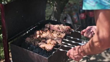 Bir adam, sıcak kömürlerin üzerinde cızırdayan şiş şiş şişlerini ustalıkla çevirir, yemek pişirmeyi bile garantiler ve lezzetli, dumanlı bir char....
