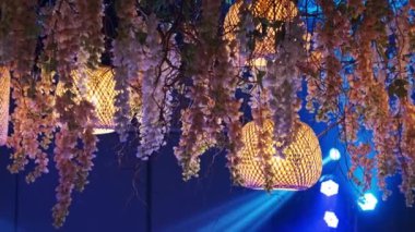 Kademeli çiçek çelenkleriyle süslenmiş bambu fenerlerin büyüleyici bir düzeni bir etkinlikte romantik ve şenlikli bir atmosfer yaratır..