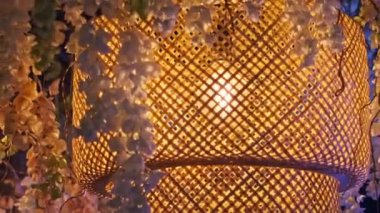 İki güzel bambu lambası, bir yuvarlak ve bir kare, salkım çiçekleriyle süslenmiş bir alan. İç tasarım, Asya estetiği ve rahat ortamlar içeren projeler için mükemmel..