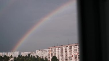 Fırtınadan sonraki umut ve güzelliğin sembolü olarak, bir şehir siluetinin üzerinde canlı bir gökkuşağı beliriyor. Renkli manzara, şehir manzarasıyla çelişiyor ve büyüleyici bir manzara yaratıyor..
