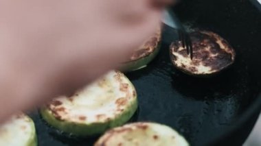 Kabak dilimlerinin sıcak bir tavaya fırlatılması, pişirme sürecini ve sebzelerin kahverengisini gözler önüne seriyor..