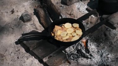 Kamp ateşinde tavada cızırdayan tavuk ve patates. Basit ve lezzetli bir açık hava yemeği..