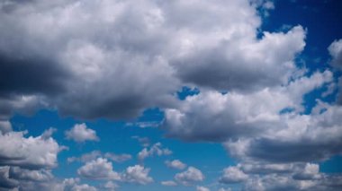 Çarpıcı, fırtınalı bulutların zamanı canlı mavi gökyüzünde hızla ilerliyor. Küçük, tüylü beyaz bulutlar yaklaşan karanlığa karşı kontrasttır..