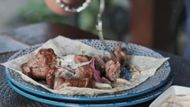 Bir adamın ellerinin bir parça ızgara eti kremalı sosa batırdığı yakın plan bir fotoğraf. Lokantada lezzetli et yemekleri yeme fikri.