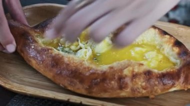Kadınların elleri Adjarian Khachapuri 'den bir parça koparıp erimiş peynir ve yumurta sarısı karışımına batırıyor. Geleneksel Gürcü gıda kavramının tadını çıkarıyorum.