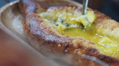 Geleneksel bir Gürcü yemeği olan Adjarian Khachapuri 'nin yumurta sarısı ve sulguni peynirli eritilmiş peynirini yakından çek. Ağız sulandırıcı, dandik güzellik konsepti.