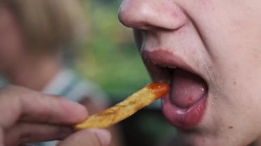 Yavrunun ağzının patates kızartması yerken çekilen yavaş çekim görüntüleri. Sağlıksız yeme alışkanlıkları, abur cubur, çocukluk obezite konsepti.