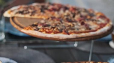 Ahşap tezgahlarda servis edilen ve yemek meraklıları için cazip bir sahne oluşturan çeşitli malzemelerle yeni pişmiş iki pizzanın yakın plan çekimi..