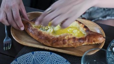 Lezzetli bir Adjarian khachapuri, geleneksel bir Gürcü yemeği, erimiş peynir ve yumurta sarısı ile ahşap bir tabakta sunulur..