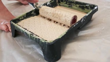 Yavaş çekim: Bir boya silindiri, duvar boyası için hazırlanan bej renkli bir tepsiye sarılıp sarmalanır. Damlayan boyayı kapat, DIY ve ev yenileme videoları için ideal..