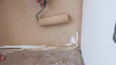 Duvarı boya rulosuyla boyayan bir kadının yakın çekimi. Yenileme ve ev geliştirme, yavaş çekim.