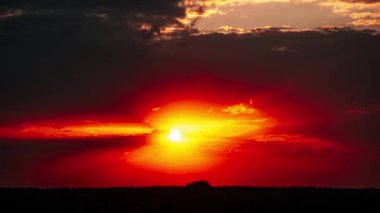 Canlı kırmızı ve turuncu renkleri ile nefes kesici bir günbatımı, karanlık bulutlarla sakin bir atmosfer yaratıyor. Doğa ve manzara görselleri için mükemmel, akşam gökyüzünün güzelliğini vurguluyor..