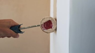 Yenileme işleminin detaylarını vurgulayarak, bir erkeğin yavaş çekimde beyaz bir duvar bejini boya rulosuyla boyarken.