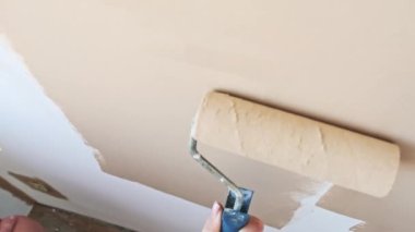 Beyaz bir duvar bejini rulo ile boyamak. Üst bakış açısı. Ev yenileme, DIY projesi, iç dekorasyon.