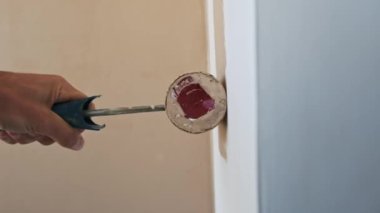 Adamın biri beyaz bir duvar bejini boya rulosuyla boyuyor. Duvarları yavaş çekimde boyama işlemi....