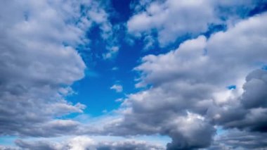 Mavi gökyüzüne karşı hızlı hareket eden beyaz ve gri kümülüs bulutlarının zamanı. Herhangi bir proje için mükemmel arkaplan.