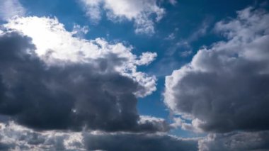 Derin mavi gökyüzünde hareket eden güzel bulutların zamanı. Güneş bulutların arasından parlıyor, çarpıcı bir görüntü yaratıyor..