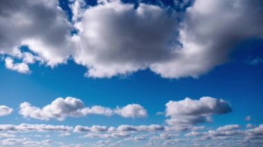 Derin mavi gökyüzünde ilerleyen tüylü bulutların sakin bir zaman atlaması. Barışçıl ve rahatlatıcı bir atmosfere ihtiyaç duyan projeler için mükemmel bir arka plan..
