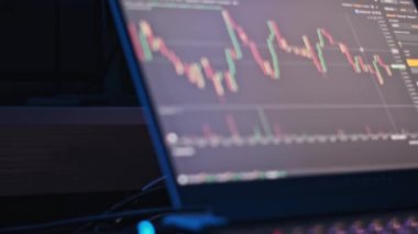 Finansal ve teknolojik projeler için ideal, aydınlatılmış klavye ile dizüstü bilgisayar ekranında gösterilen borsa veri ve grafikleri.