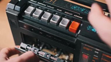 Bir kaset eski bir çalıcıya yerleştirilir ve çalma düğmesine basılır. Retro teknoloji ve müzik konsepti.