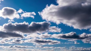 Beyaz ve gri bulutlar canlı mavi bir gökyüzünde sürükleniyor, barışçıl ve huzurlu bir atmosfer yaratıyor. Doğa ve seyahat projeleri için mükemmel..