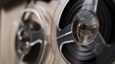 Klasik bir makaradan makaraya kayıt cihazının yakın çekim görüntüsü. Manyetik bant makaralarda sorunsuzca hareket ediyor. Retro titreşim eklemek için harika..