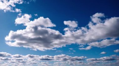 Beyaz bulutlar canlı, masmavi bir gökyüzünde sürükleniyor, barışçıl ve huzurlu bir atmosfer yaratıyor. Doğa ve seyahat filmleri için ideal..