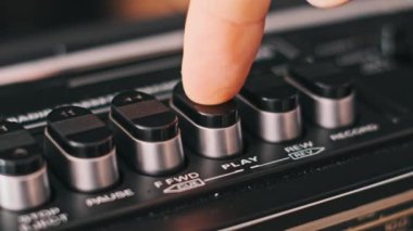 Retro radyo kasetçaların çalma tuşuna basan parmağın yakın plan görüntüsü. Nostalji ve klasik teknolojiyi çağrıştıran projeler için ideal..