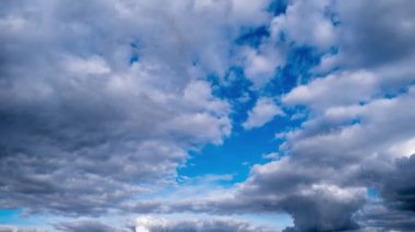 Karanlık ve aydınlık bulutların çarpıcı zaman çizelgesi canlı mavi gökyüzünde hareket ederek büyüleyici bir güç ve güzellik gösterisi yaratıyor..