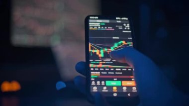 Bir el, şifreli döviz alım satım grafiklerini pazar verilerinin bulanık geçmişiyle karşılaştırmak için akıllı telefon kullanıyor. Fintech ve mobil ticaret içeriği için mükemmel.