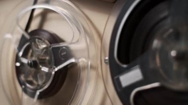 Eski bir makaradan makaraya kayıt cihazının yakın çekim görüntüsü. Kaset dönüyor, nostaljik ve geçmişe dönük bir his yaratıyor. Müzik, tarih veya teknolojiyle ilgili projeler için mükemmel.