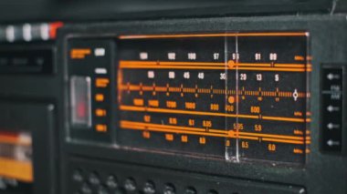 AM FM bantlı ve frekans işaretleyicili klasik bir radyonun ayrıntılı görüntüsü. Turuncu ölçek, geçmişe dönük bir cazibe yayar..