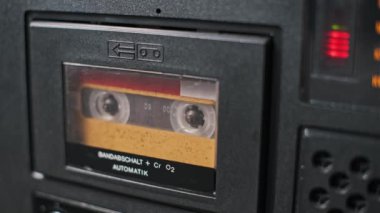 Eski bir teybin içindeki kasetin yakın çekim görüntüsü. Teyp ve cihaz mekaniği nostaljiyi çağrıştırıyor, müzik veya klasik temalı görseller için mükemmel..