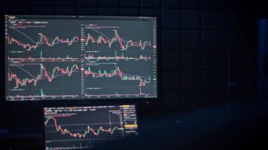 Karanlık bir odada bilgisayar monitöründe sergilenen borsa grafikleri ve verileri mali analiz ve yatırım hissi yaratıyor..