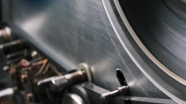 Eski bir makaradan makaraya kayıt cihazının detaylı mekanik özelliklerini gösteren yakın çekim bir görüntü. Karmaşık çalışmalar ve pürüzsüz hareketler görsel olarak ilgi çekici bir sahne sağlıyor. Arkaplan veya teknik projeler.