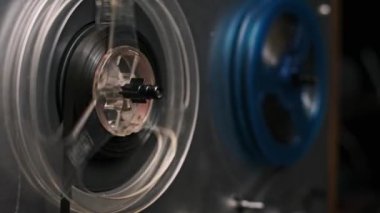 Eski bir makaradan makaraya dönen ses makinesinin detaylı bir görüntüsü. Şeffaf plastik ve koyu bant büyüleyici bir görüntü yaratır. Retro temalı projeler için mükemmel.