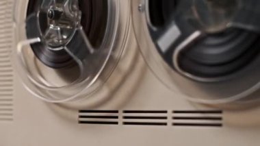 Yumuşak ışıklandırmada dönen makaralara odaklanan eski bir makaradan makaraya kayıt cihazının nostaljik bir görüntüsü. Retro teknolojiyi ve analog sesin sıcaklığını kutluyor.