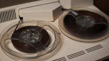 A detailed look at a spooling tape on a vintage reel-to-reel recorder in motion. The image captures the tactile charm of analog technology with a nostalgic aesthetic.