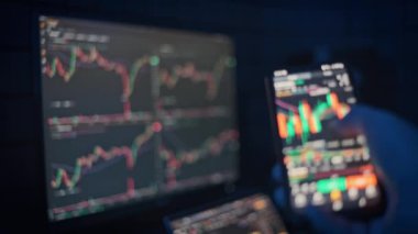 Arka planda ticari çizelgeleri gösteren bulanık bir bilgisayar ekranı olan ve pazar eğilimlerini analiz eden bir kripto tüccarının yakın plan görüntüsü. Finans ve yatırım içeriği için mükemmel.
